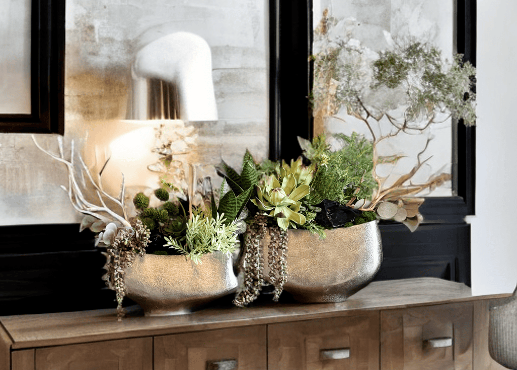 Modern floral arrangement with succulents and greenery in metallic planters on a wood console table, featuring the new style of Curate Florals rebrand